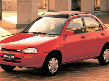 Rode Mazda 121 geparkeerd in een stedelijke omgeving.