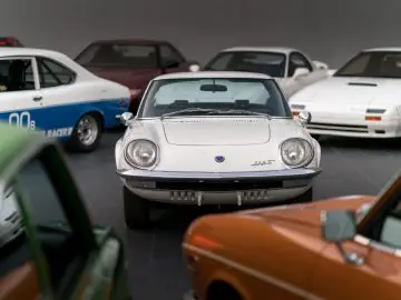 Klassieke Mazda-sportwagen tentoongesteld in een collectie met verschillende vintage voertuigen.