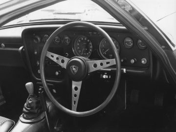 Vintage Mazda auto-interieur met een driespaaks stuurwiel en analoge meters.