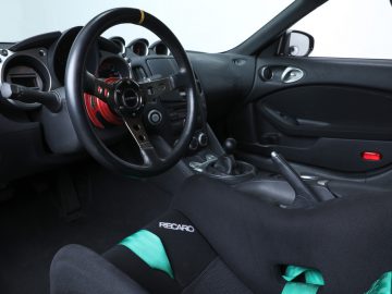 Interieur van een sportwagen, die doet denken aan een auto uit The Fast and the Furious, met Recaro-stoelen en een handgeschakelde versnellingsbak.