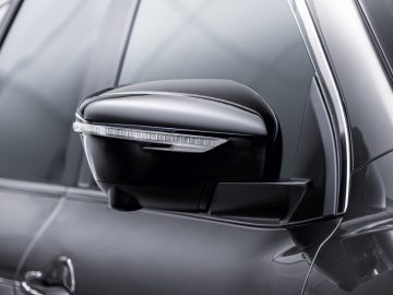 Close-up van de zijspiegel van een Nissan N-Tec-auto met geïntegreerd richtingaanwijzer.