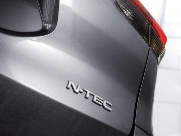 Close-up van het achterste zijpaneel van een auto met het Nissan "N-Tec"-embleem.