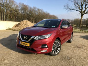 Rode Nissan Qashqai buiten geparkeerd op een zonnige dag.