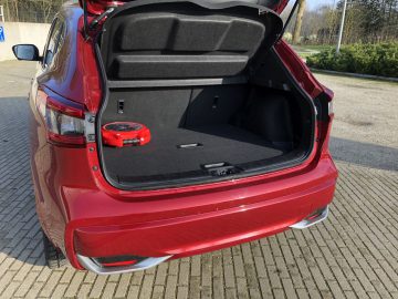 Rode Nissan Qashqai met een open kofferbak, waardoor een ruime laadruimte zichtbaar is en een rode speelgoedauto erin.