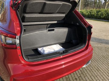 Rode Nissan Qashqai met een open kofferbak met daarin één verpakt item.