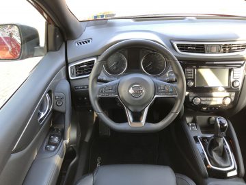 Binnenaanzicht van een Nissan Qashqai met het stuur, het dashboard en de middenconsole.