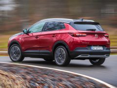 Een rode Opel Grandland X in beweging op een natte weg, die dynamisch rijgedrag laat zien.