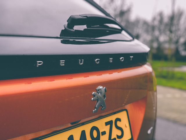 Close-up van het achterste embleem en modelopschrift op een oranje Peugeot 2008-auto.