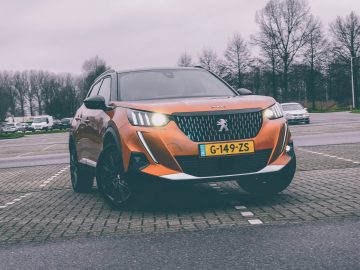 Een moderne Peugeot 2008 SUV die overdag op een verharde weg rijdt.