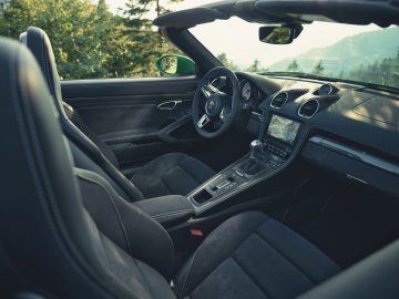 Binnenaanzicht van een Porsche 718 GTS met leren stoelen, stuur, dashboard en middenconsole met beeldscherm.