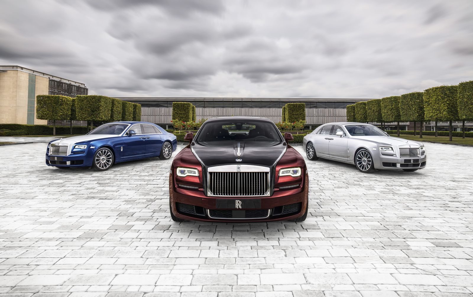 Drie Rolls-Royce-auto's geparkeerd voor een gebouw.