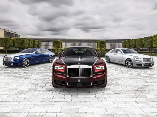 Drie Rolls-Royce-auto's geparkeerd voor een gebouw.