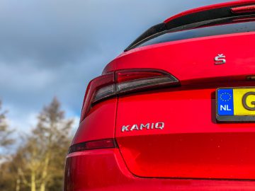Close-up van een rode Skoda Kamiq-auto van achteren met een Europees kenteken, genomen op een bewolkte dag.