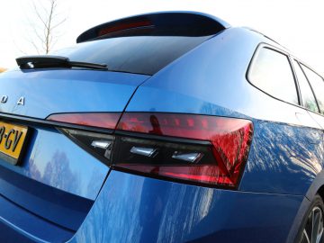 Een close-up van een blauwe Skoda Superb-auto vanuit de achterste hoek, waarbij het ontwerp van het achterlicht wordt benadrukt.