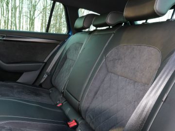 Binnenaanzicht van een Skoda Superb met lederen en stoffen autostoelen met hoofdsteunen.