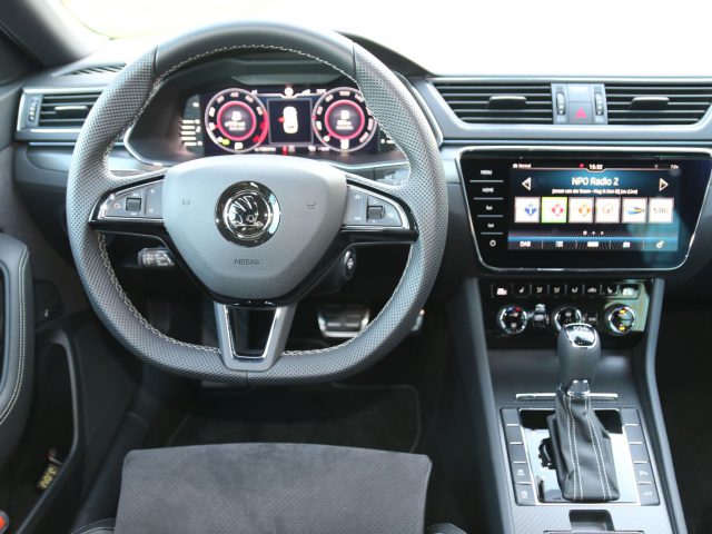 Binnenaanzicht van het moderne dashboard van een Skoda Superb met een stuurwiel met bedieningselementen, een digitaal instrumentenpaneel en een centraal infotainmentsysteem met aanraakscherm.