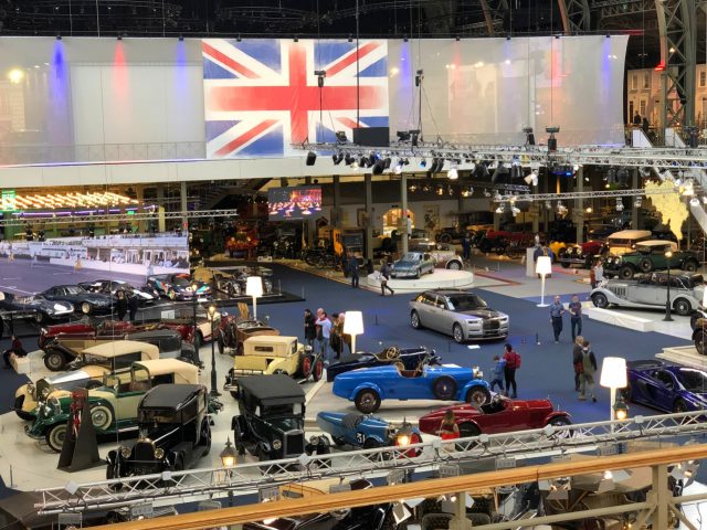 Klassieke autotentoonstelling met een verscheidenheid aan vintage voertuigen onder een grote 'So British'-vlag.