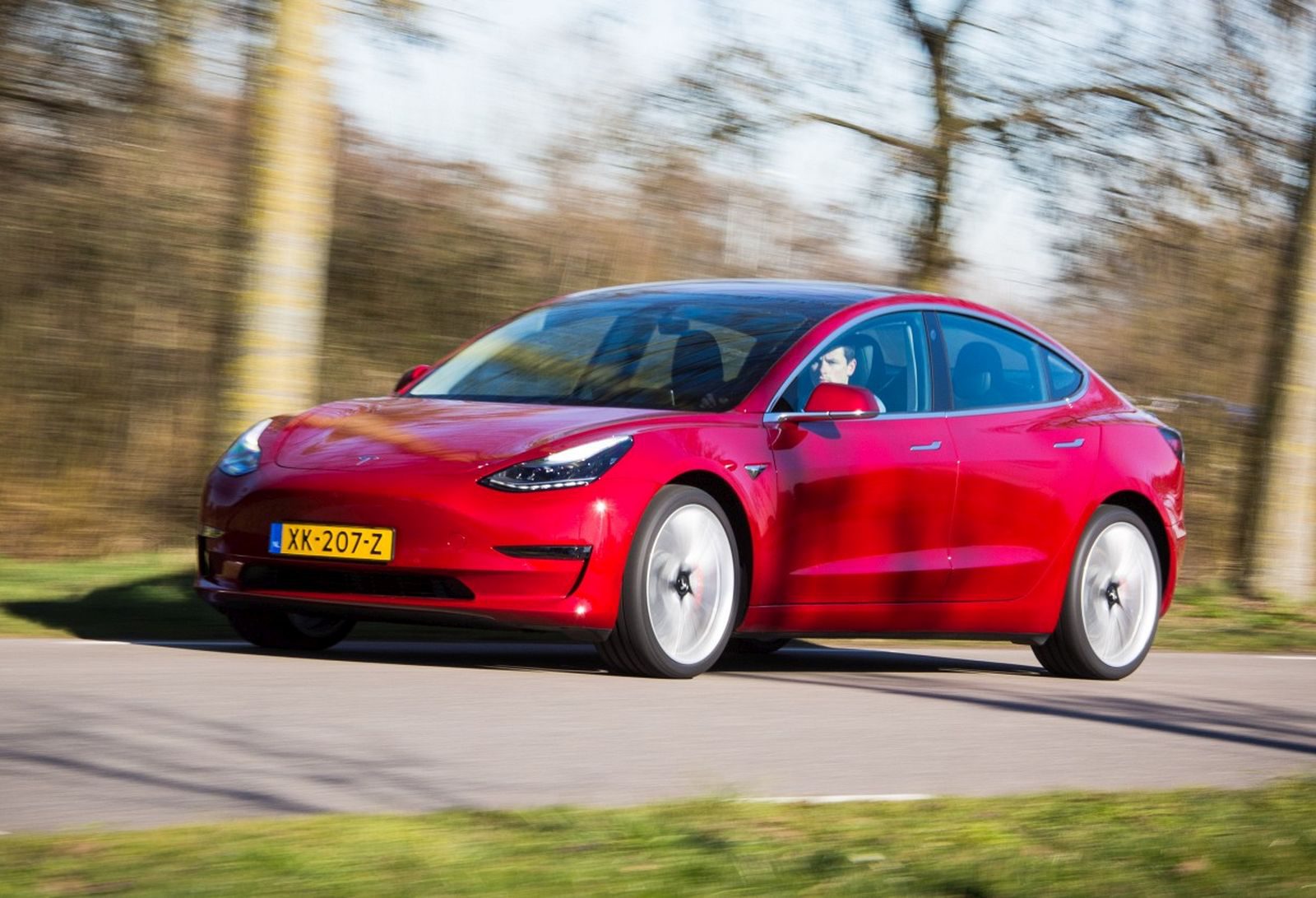De Tesla Model 3 rijdt over een weg.