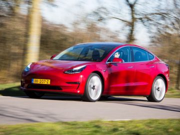 De Tesla Model 3 rijdt over een weg.