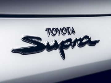 Close-up van het Toyota Supra-embleem op de carrosserie van een auto.
