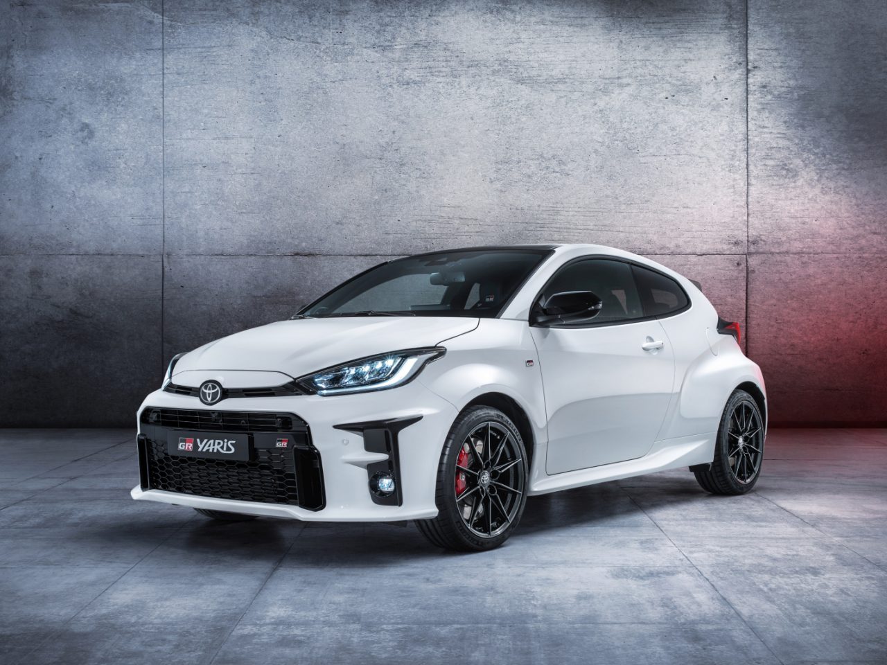 Witte Toyota GR Yaris geparkeerd voor een betonnen muur.