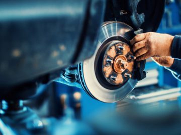 Een monteur werkt aan de remmen van een auto in een autogarage.