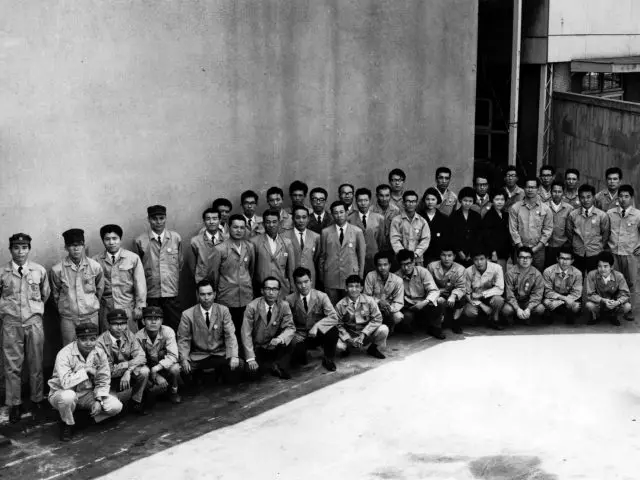Een groep mannen in uniform poseert voor een groepsfoto tegen de achtergrond van een Mazda-dealer.