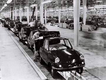 Vintage zwart-witfoto van arbeiders en auto's op een Mazda-auto-assemblagelijn.