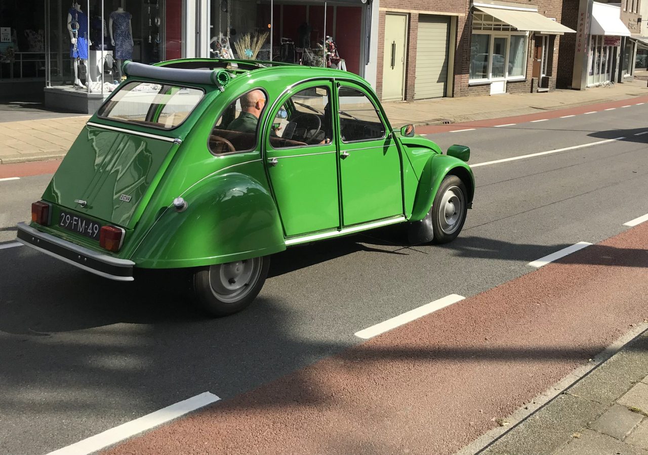 Een klassieke groene Citroën 2cv oldtimer geparkeerd in een stadsstraat.