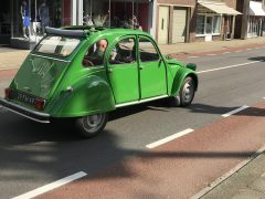 Een klassieke groene Citroën 2cv oldtimer geparkeerd in een stadsstraat.