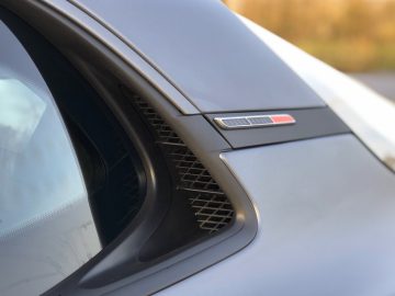 Close-up van de zijkant van een Alpine A110 S-auto met de nadruk op de ventilatieopening en het badgedetail.