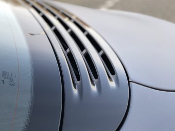 Close-up van de achterruit van een Alpine A110 S met geïntegreerde ontdooilijnen en een hoog gemonteerd remlicht zichtbaar door het getinte glas.