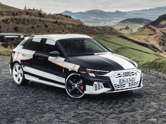 Een Audi A3 geparkeerd op een geplaveide weg met een schilderachtig heuvelachtig landschap op de achtergrond.