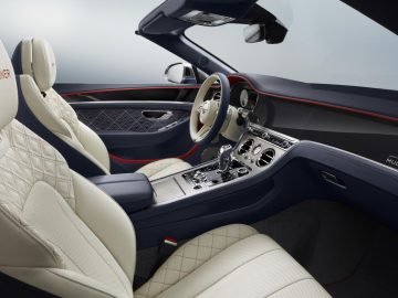 Luxe Bentley Continental GT Mulliner Convertible-interieur met gewatteerde lederen stoelen, houten en metalen accenten en een middenconsole met verschillende bedieningselementen.