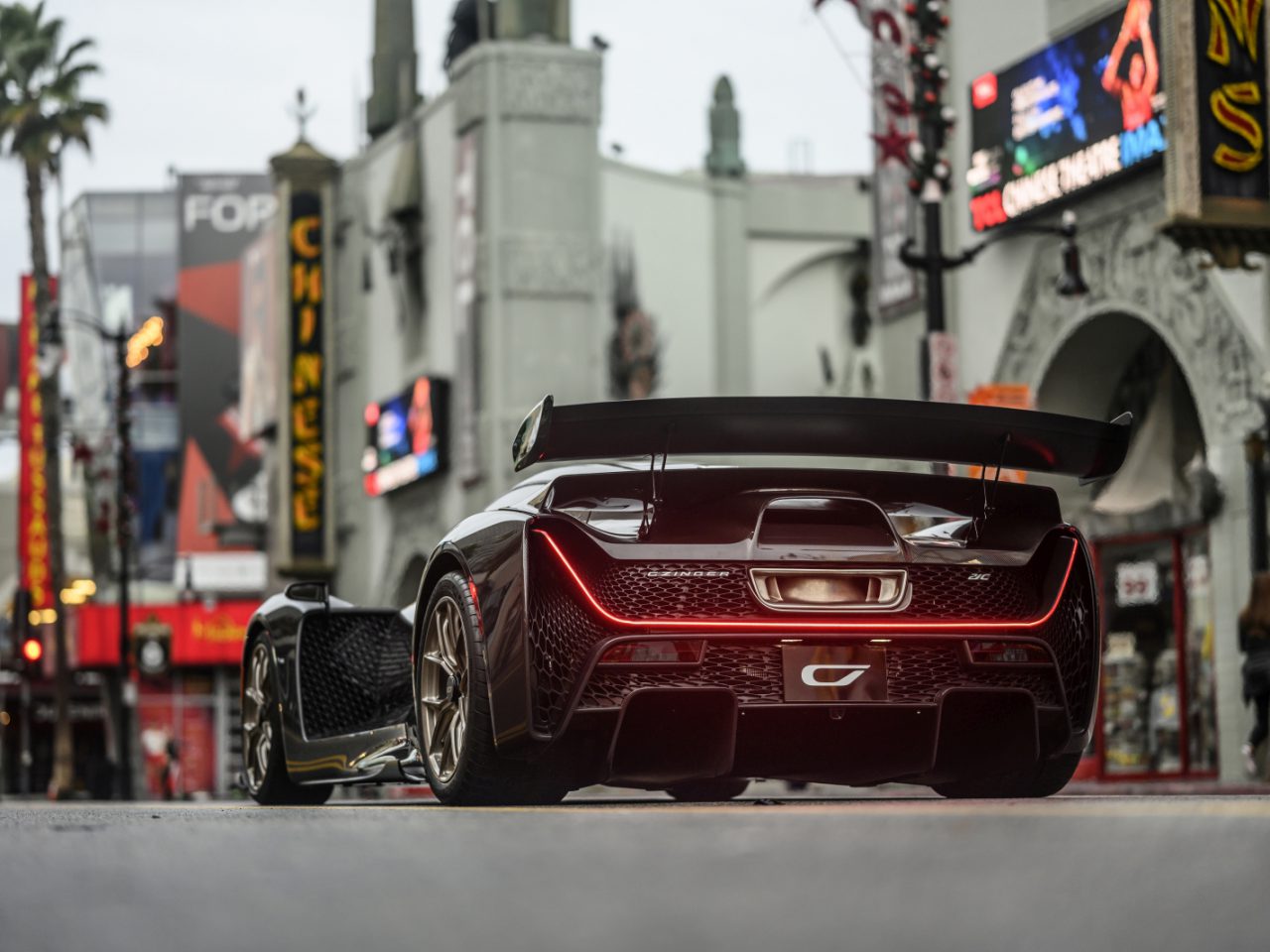 Krachtige Czinger 21C-sportwagen in een stadsstraat met iconische theaters en bewegwijzering op de achtergrond.
