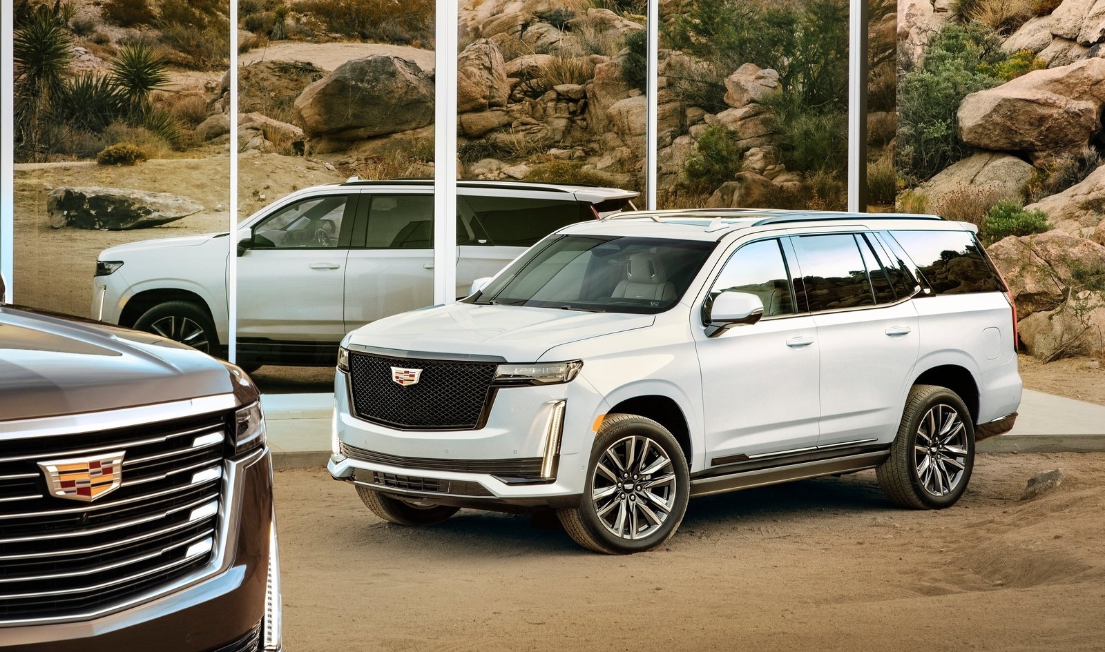 Luxe Cadillac Escalade SUV's tentoongesteld in een woestijnachtige omgeving.