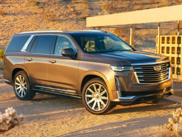 Cadillac Escalade luxe SUV geparkeerd in een woestijnlandschap bij zonsondergang.