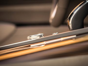 Close-up van interieurdetails van de Cadillac Escalade-luxeauto met focus op ventilatieopeningen en houten afwerking.