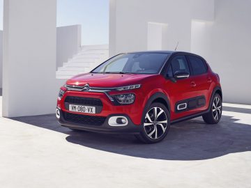 Rode Citroën C3 geparkeerd in een moderne, witte architectonische setting.