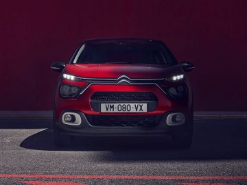 Rode Citroën C3 hatchback-auto geparkeerd voor een rode muur.