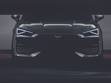 Vooraanzicht van een moderne Cupra Leon-auto met LED-koplampen en een opvallende grille met een driehoekig logo.