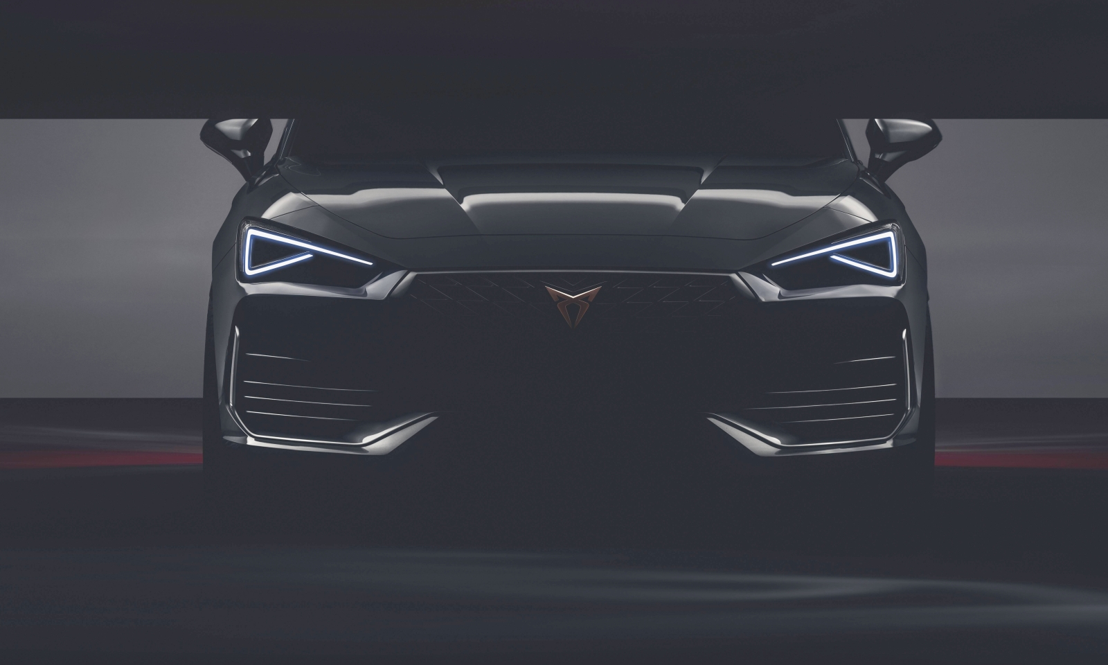 Vooraanzicht van een moderne Cupra Leon-auto met LED-koplampen en een opvallende grille met een driehoekig logo.