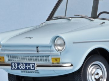 Close-up van een lichtblauwe vintage DAF 33-modelauto met details van de voorkant, waaronder koplampen, grille en een embleem op de motorkap.