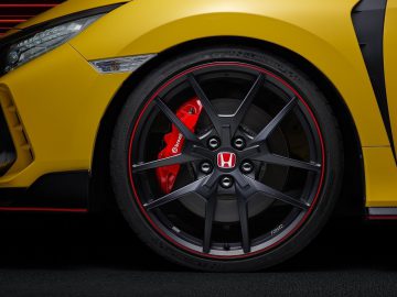 Close-up van het zwarte wiel van een gele Honda Civic Type R Limited Edition met rode remklauw en Honda-embleem.