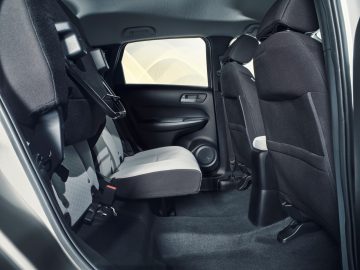 Binnenaanzicht van het achterste passagierscompartiment van een moderne Honda Jazz, met de nadruk op het ontwerp van de schone stoffen stoelen en het deurpaneel.