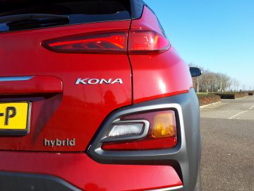 Close-up van de achterkant van een rode Kona Hybrid, met de nadruk op het achterlicht en de badges.
