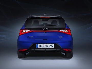 Blauwe Hyundai i20 geparkeerd tegen een donkere achtergrond met dynamische lichtpatronen.