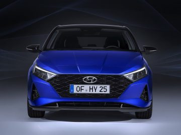 Blauwe Hyundai i20 tentoongesteld met een dynamische achtergrond.