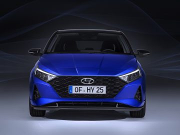 Een blauwe Hyundai i20-auto tentoongesteld onder dramatische verlichting.