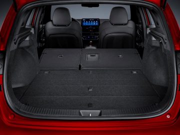Lege kofferbak van een rode Hyundai i30 met neergeklapte achterbank, waardoor een ruime laadruimte zichtbaar is.